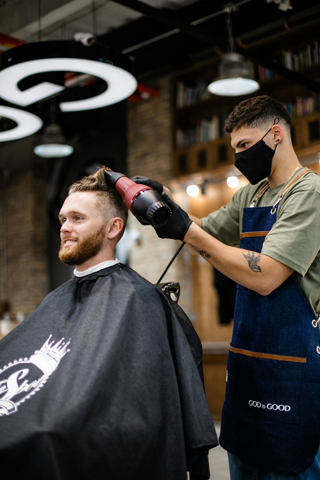 Barbiere al lavoro che asciuga i capelli a un cliente soddisfatto